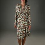 The woman wears a patterned wrap dress with long sleeves.