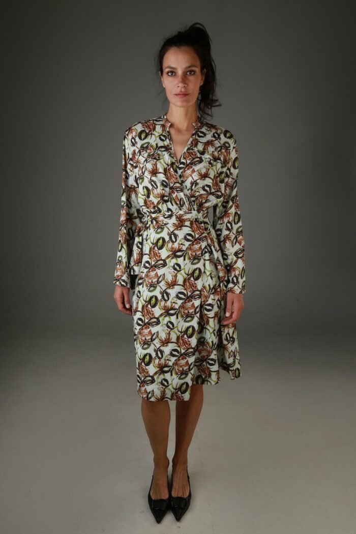 The woman wears a patterned wrap dress with long sleeves.