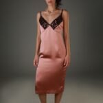 Žena nosi midi haljinu od smeđeg satena sa crnom čipkom na dekolteu.