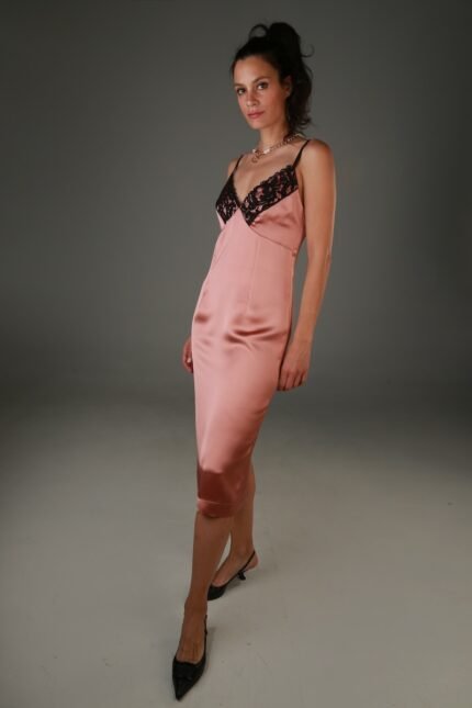 The woman wears a brown satin midi dress with black lace at the neckline.