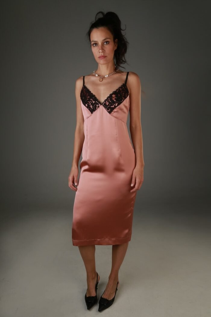 The woman wears a brown satin midi dress with black lace at the neckline.