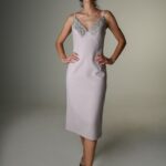 The woman wears a midi gray dress with straps.