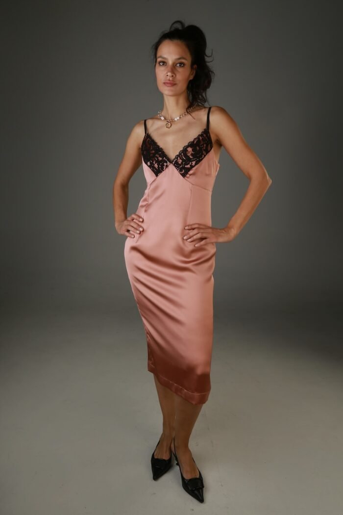 The woman wears a brown satin midi dress with black lace at the neckline.