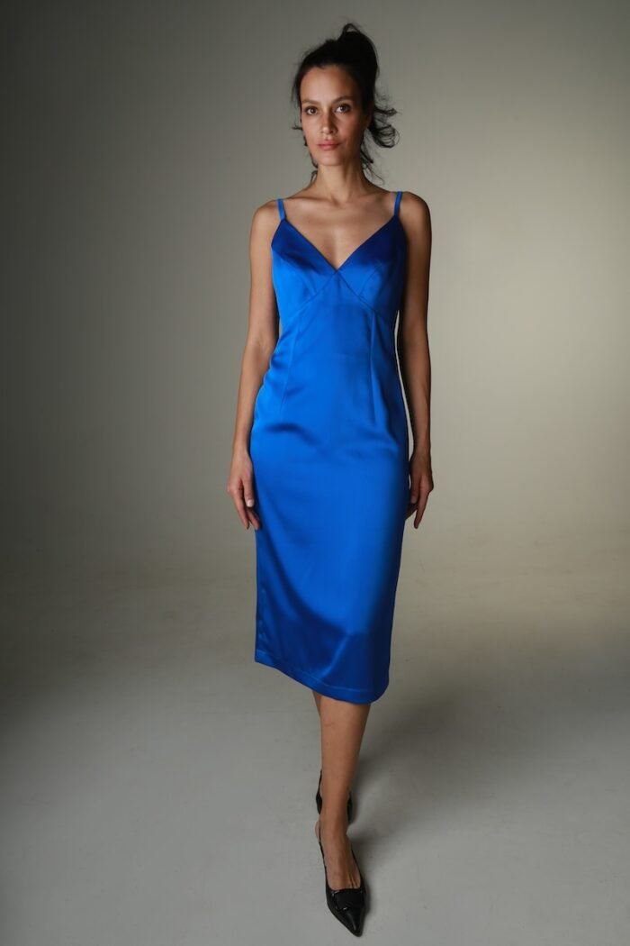 The woman wears a blue satin midi-length dress with straps and a V-neckline.