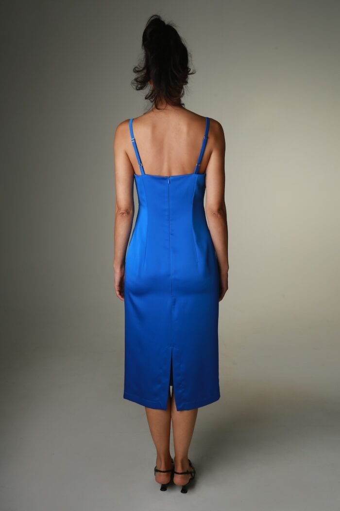 The woman wears a blue satin midi-length dress with straps and a V-neckline.