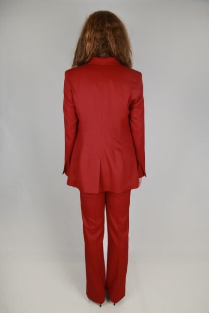 The woman is wearing a red blazer and red pants.