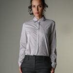 The woman wears a gray shirt with small black dots and dark gray pants.