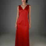 Žena nosi dugu crvenu haljinu bez rukava sa V izrezom.