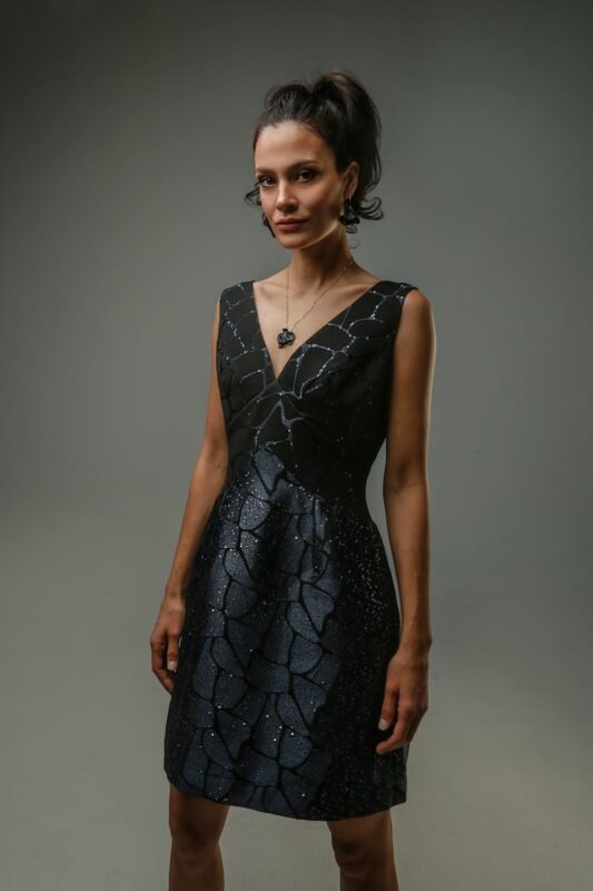 The woman wears a short, navy-black sequined dress with a V-neckline.