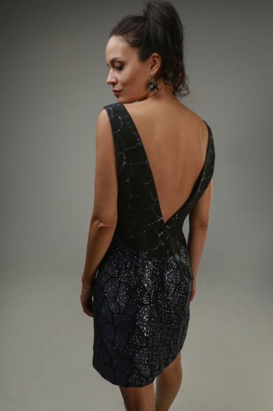 The woman wears a short, navy-black sequined dress with a V-neckline.