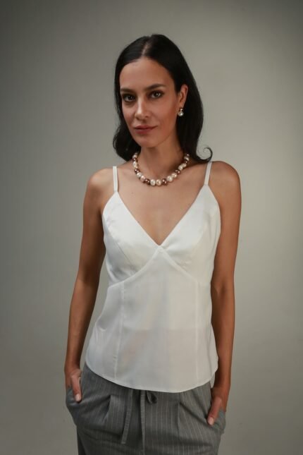 The woman wears a white top with straps.