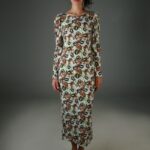 The woman wears a patterned, midi dress with long sleeves.