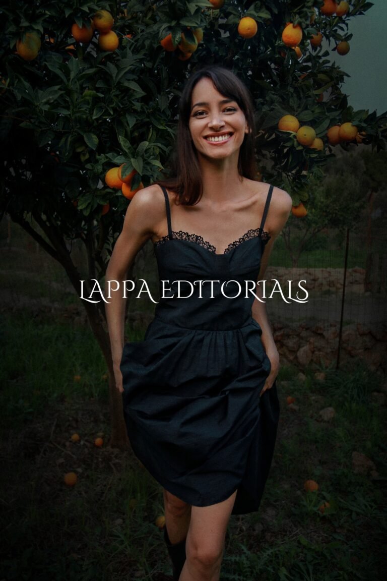 WOMAN WEARING BLACK DRESS WITH STRAPS PHOTOGRAPHED IN FRONT OF THE CITRUS TREE.