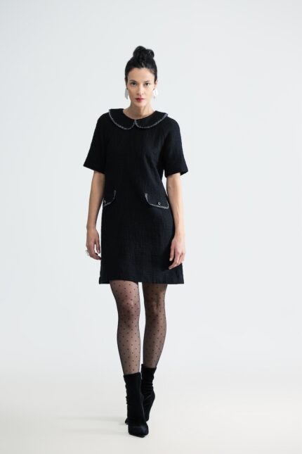 The woman wears a short black COURTNEY dress with short sleeves and a Peter Pan collar.