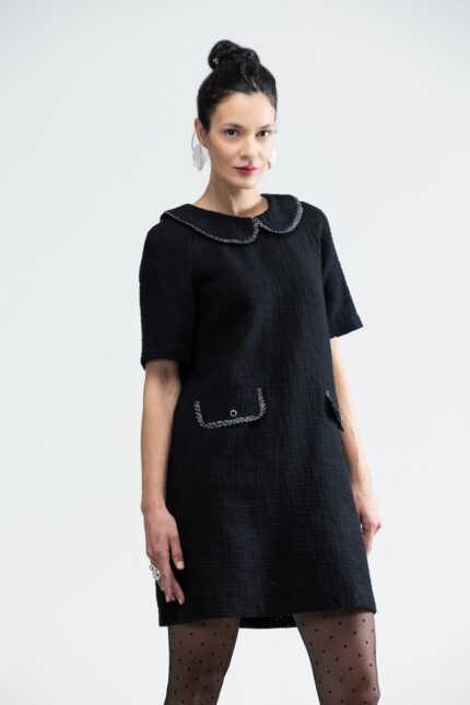 The woman wears a short black COURTNEY dress with short sleeves and a Peter Pan collar.