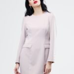 Devojka nosi kratku svetlo-ljubičastu haljinu sa dugim rukavima.