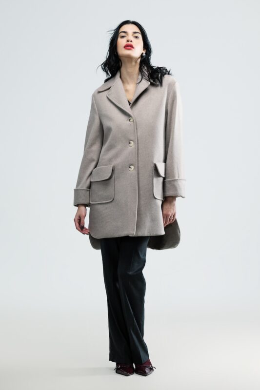 The girl is wearing a beige woolen coat.