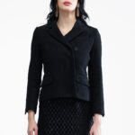 Devojka nosi crni strukirani, kratki blejzer.