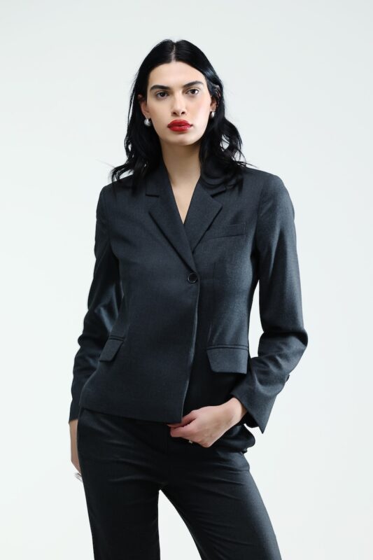 The girl wears a tight, grey, waisted blazer.