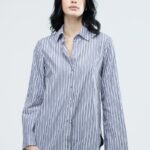 The girl is wearing a striped LINA shirt in a relaxed fit.