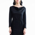 Devojka nosi kratku crnu haljinu sa dugim rukavima.