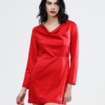 Devojka nosi kratku crvenu haljinu sa dugim rukavima i padajućim izrezom.