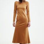 The woman wears a brown midi-length dress with long sleeves.