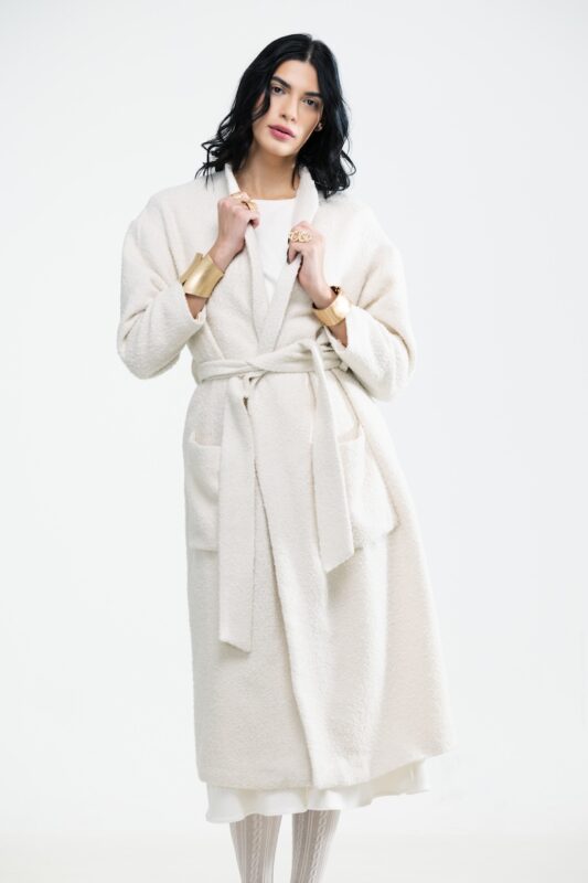 The girl wears a cream white tie coat.