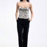 Devojka nosi crne uske pantalone REBECCA i zlatni top.