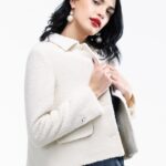 The girl wears a short white boucle blazer.
