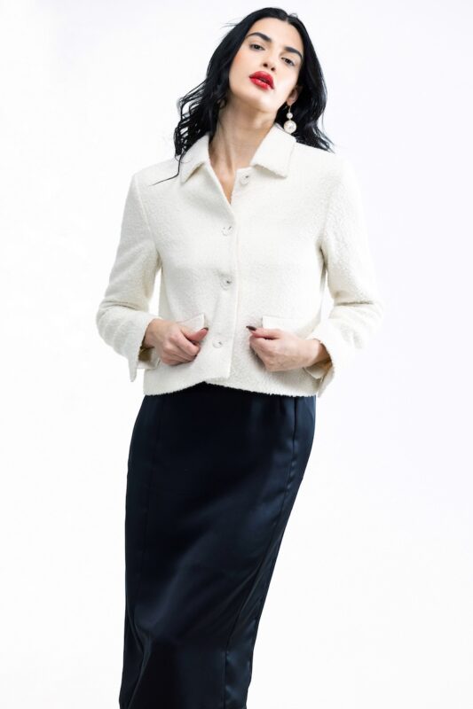 The girl wears a short white boucle blazer.