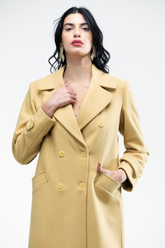 The girl wears a yellow double-breasted midi-length coat.