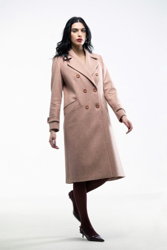 The girl wears an apricot double-breasted midi coat.