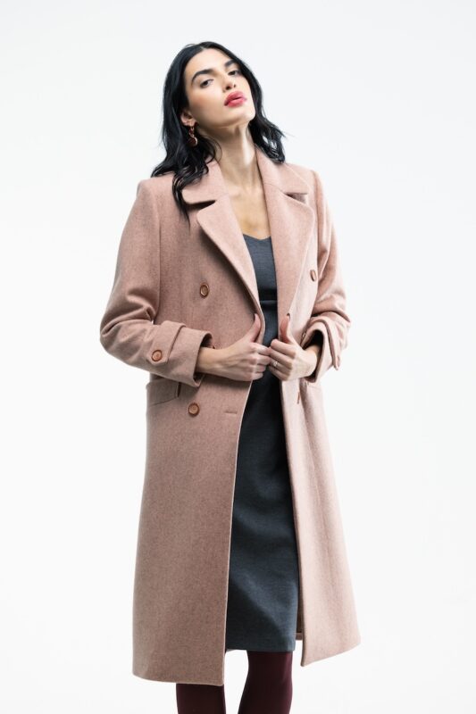 The girl wears an apricot double-breasted midi coat.