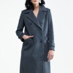 Žena nosi sivi kaput midi dužine sa dvorednim kopčanjem.