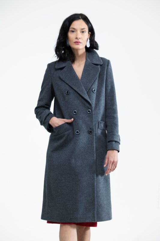 The woman wears a gray midi-length coat with a double-breasted button.