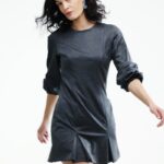 Žena nosi kratku sivu haljinu sa dugim rukavima.