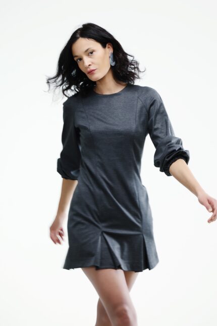 The woman wears a short gray dress with long sleeves.