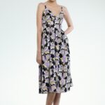 Model nosi midi haljinu na bretele u ljubičasto-crnom dezenu.