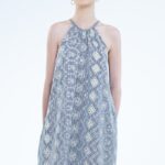 Devojka nosi kratku plavo-belu haljinu na pruge, sa bež vezom po tkanini.