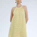 Model nosi kratku žutu haljinu od čipke.