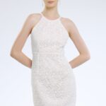 Model nosi kratku haljinu od bele čipke sa otvorenim leđima.