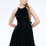 Model nosi kratku crnu haljinu od lana sa karnerom.