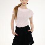 Model nosi crni laneni šorts i roze majicu kratkih rukava.