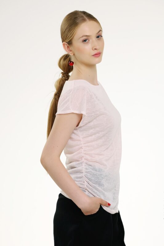 Model nosi bledo roze bluzu kratkih rukava.