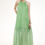 Model nosi dugu zelenu haljinu sa lepršavim karnerom.