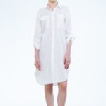 Model nosi midi košulju-haljinu od belog pamuka sa vezom po tkanini.