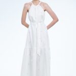 Model nosi dugu belu haljinu bez rukava sa karnerom.