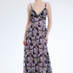 Model nosi dugu haljinu na bretele ljubičasto-crnog dezena.