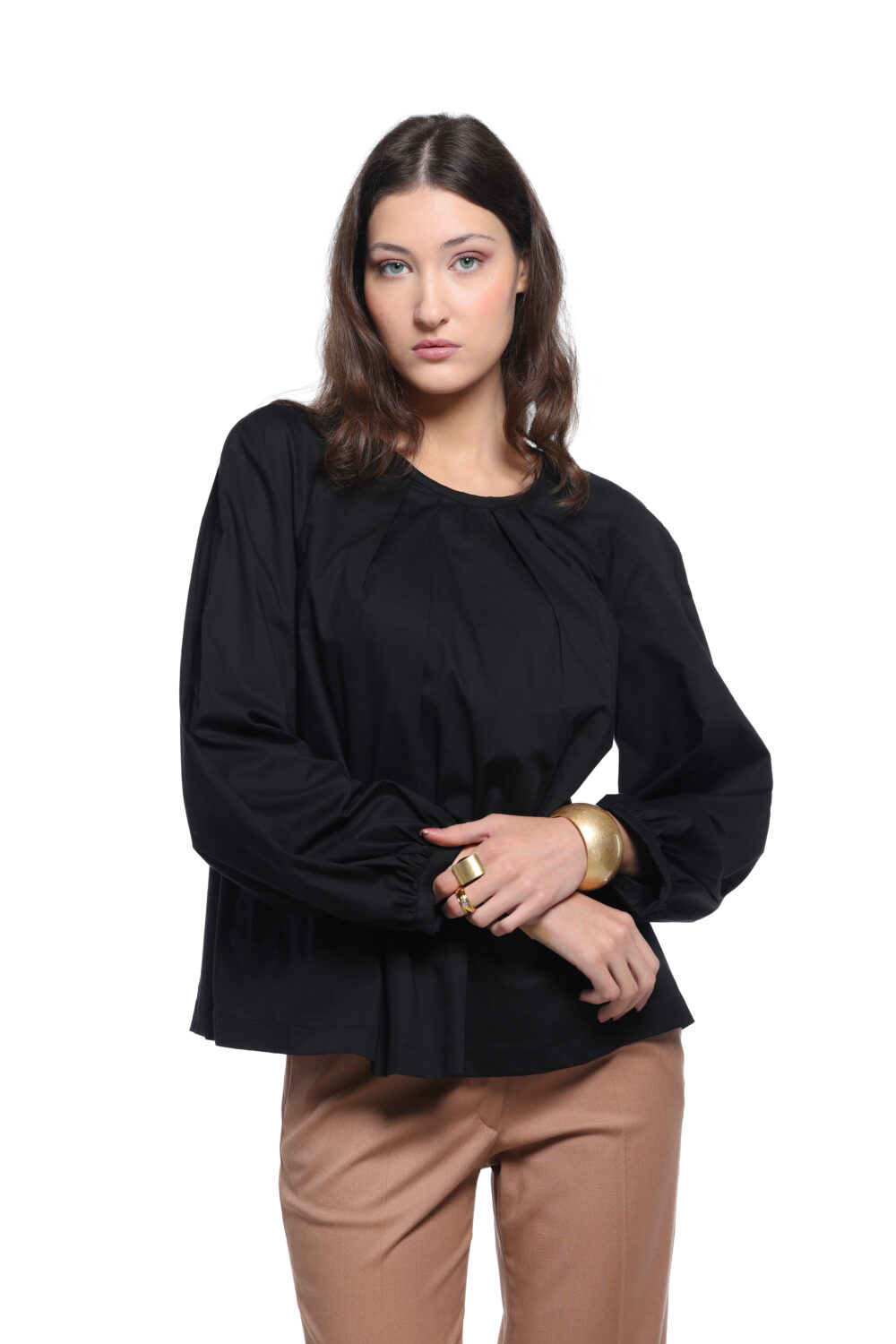 Model nosi crnu ALEKSA bluzu uparenu sa kamel pantalonama na beloj pozadini.